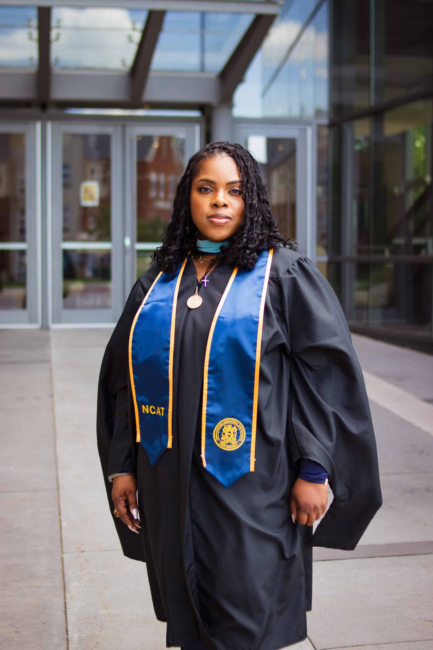 Graduation graduate in cap and gown outside university building.