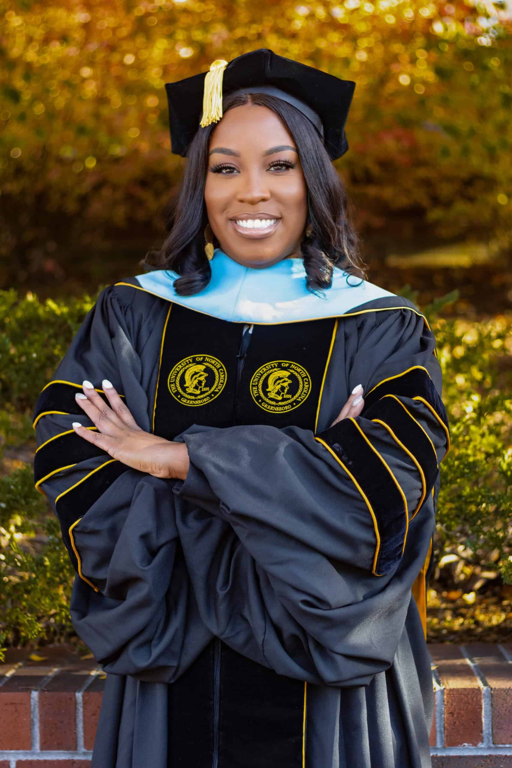 Graduation woman in cap and gown smiling outdoors.