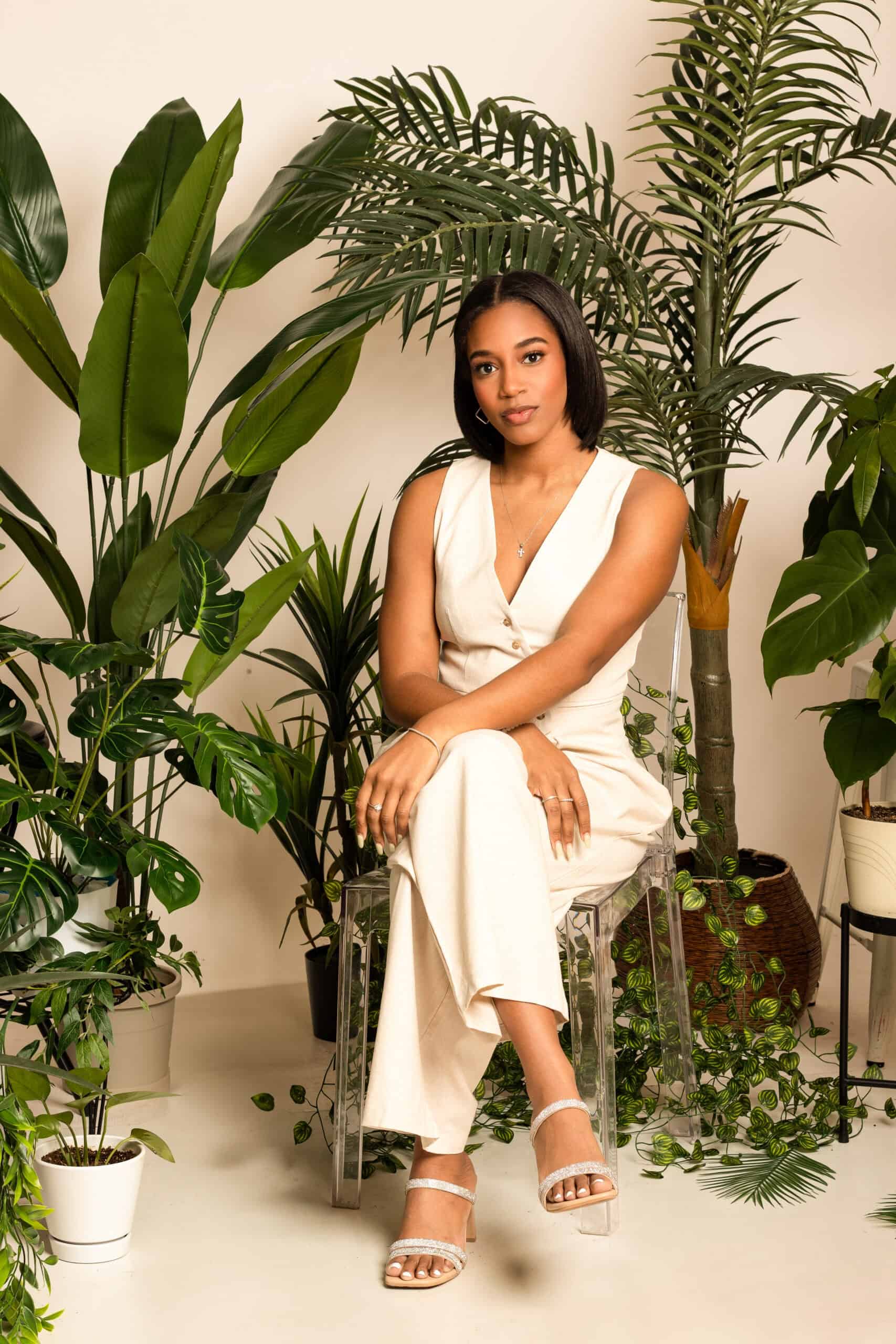 Woman in white jumpsuit surrounded by tropical indoor plants for a fresh, natural look.