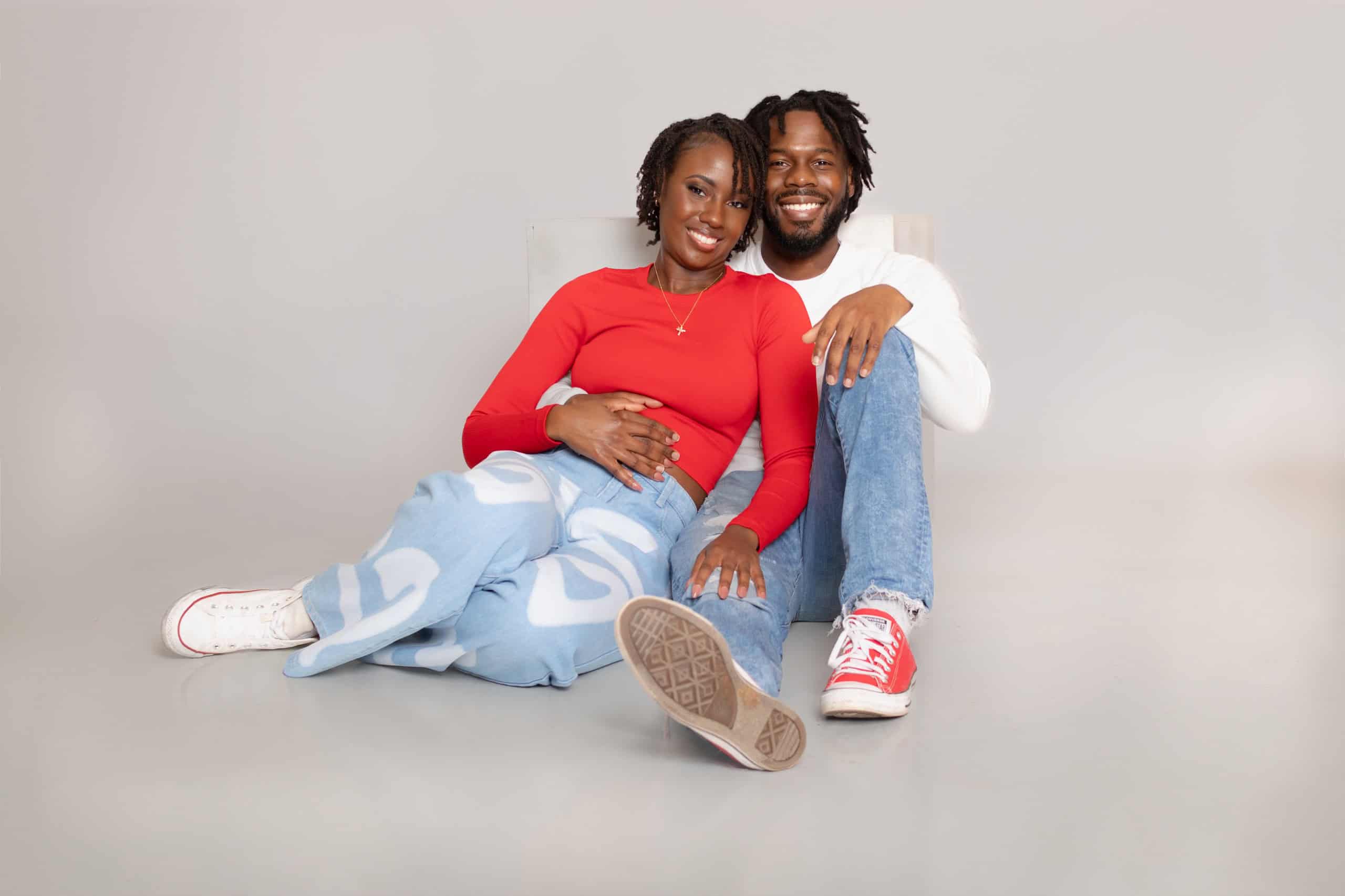 Joyful couple sitting on the floor, smiling and embracing each other.