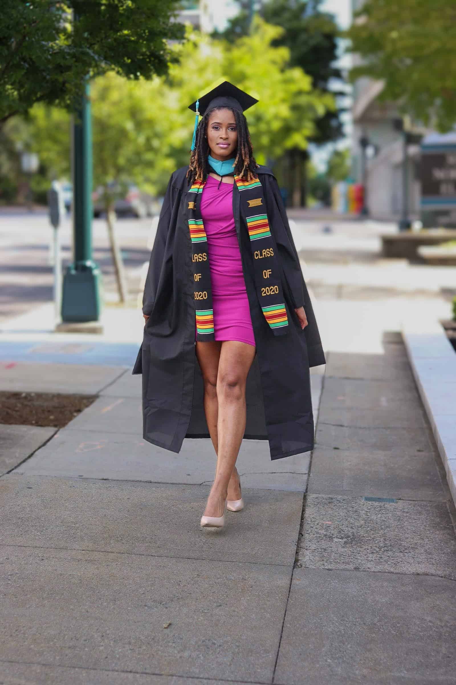 Graduation graduate in cap and gown walking outdoors on campus.